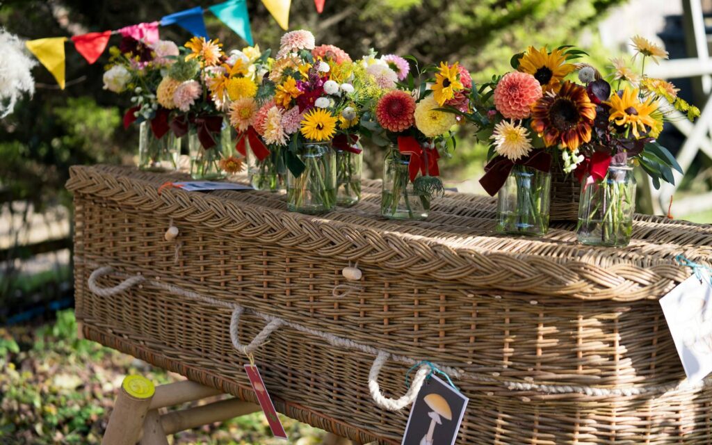 Flowers adorn a wicker coffin at a celebration